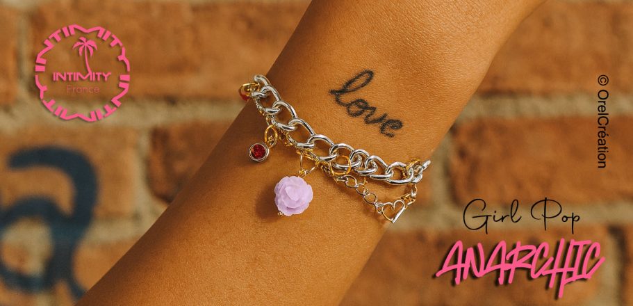 collection de créateur 2026 Poignet avec bracelets en chaîne, breloques et un tatouage "love" sur la peau.